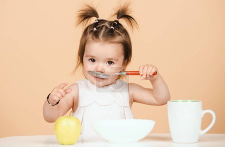 Photo for Baby eating kids food. Kid eating healthy food with a spoon at studio, isolated. Funny kids face - Royalty Free Image