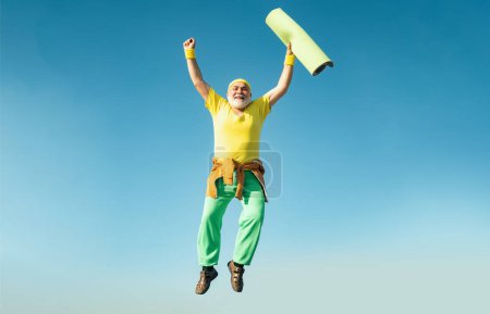Foto de Sénior divertido saltando. Viejo saltando sobre el fondo azul del cielo. Hombre mayor está disfrutando de estilo de vida deportivo. Deportiva. Ocio activo - Imagen libre de derechos