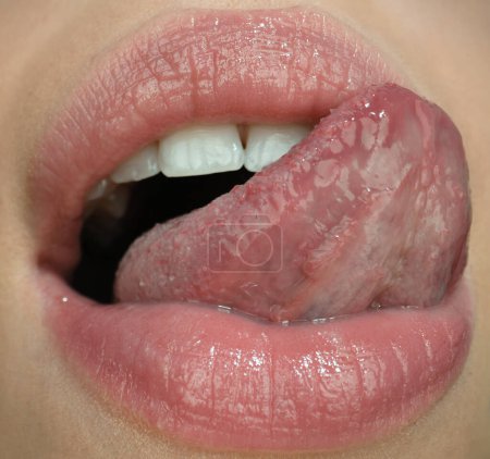Foto de Lengua sexy. Primer plano labio natural perfecto, boca femenina con la lengua hacia fuera. Labios rellenos sensuales. Macro detalle cara - Imagen libre de derechos