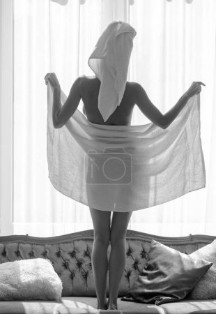 Téléchargez les photos : Vue arrière de fille sexy reposant dans la chambre de luxe un matin facile. Belle femme sensuelle relaxante portant des peignoirs et des serviettes dans la chambre d'hôtel. Ravissante tendresse corps - en image libre de droit