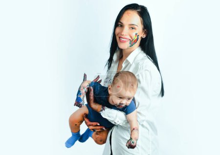 Foto de Madre de familia feliz jugando con el bebé recién nacido. Manos pintadas de colores en una hermosa familia joven. Mujer bonita sosteniendo a un bebé recién nacido en sus brazos. Fondo blanco - Imagen libre de derechos