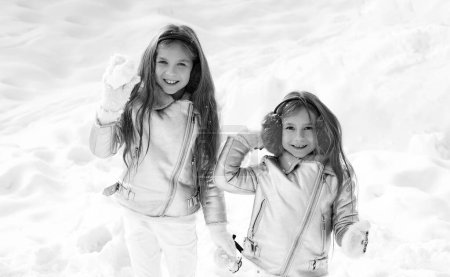 Foto de Dos niñas jugando en la nieve en invierno. Pelea de bolas de nieve. Niños de invierno divirtiéndose jugando en la nieve al aire libre. Niños lanzando una bola de nieve - Imagen libre de derechos