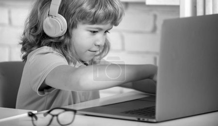 Foto de Niño niño en los auriculares estudio en línea, niño en los auriculares tomar lección web de Internet. Programación infantil Genius - Imagen libre de derechos