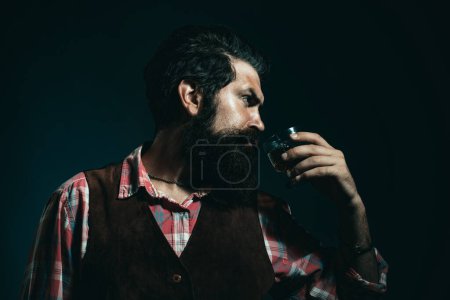 Photo for Luxury beverage concept. Stylish rich man holding a glass of old whisky. Bearded businessman in elegant suit with glass of whiskey - Royalty Free Image