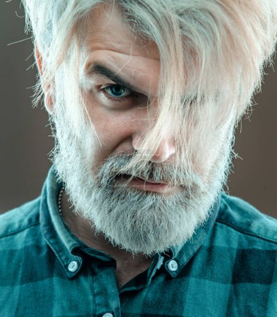 Téléchargez les photos : Gros plan du visage de l'homme latin à la mode sur fond gris. Guy à la barbe et coiffure moderne en studio - en image libre de droit