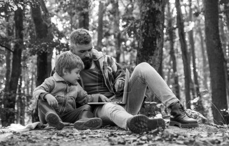 Foto de Lindo niño con su padre durante un paseo por el bosque. Padre jugando con su hijo pequeño en un picnic en el parque a principios de otoño. Padre enseñar bebé - Imagen libre de derechos