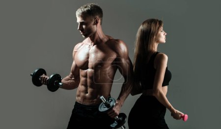 Photo for Fitness models pumping up arm with dumbbell. Sporty sexy couple with dumbbells on black studio background. Muscular sexy man and slim fit woman body - Royalty Free Image