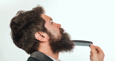 Photo for Bearded man with beard, bearded gay. Barbershop concept. Mustache men. Closeup of a young man styling his long beard with a comb - Royalty Free Image