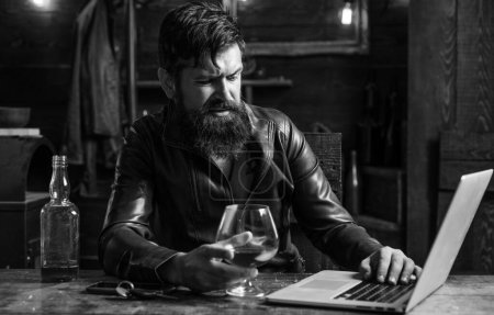Photo for Portrait of a handsome man with beard. Brutality and masculine concept. Barbershop, shaving.Macho is drinking by his laptop. Disgust - Royalty Free Image