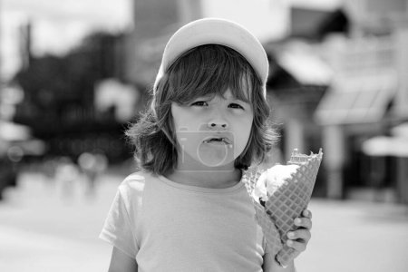 Téléchargez les photos : Un enfant qui mange de la glace. Beau petit garçon mange de la glace en été - en image libre de droit