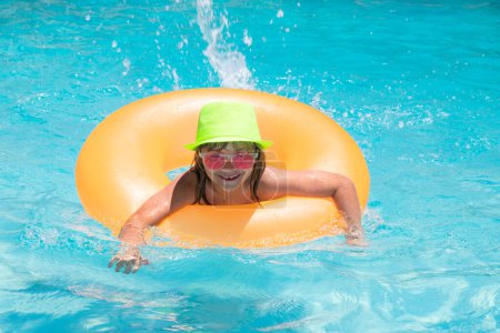 Foto de Relájate. Salpicaduras de niños en la piscina. Nadar actividad deportiva acuática en vacaciones de verano con niños. Juguetes de agua para niños, anillo flotante - Imagen libre de derechos
