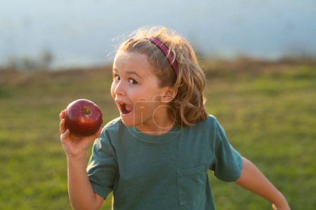 Téléchargez les photos : Manger une pomme. Joyeux adolescent avec de la pomme. Photo d'un enfant tenant une pomme. Enfant avec pomme - en image libre de droit
