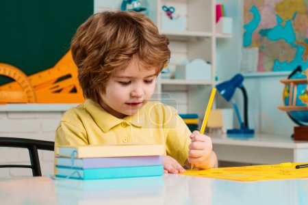 Photo for Child home studying and home education. Kid gets ready for school. Back to school. Happy smiling pupil drawing at the desk - Royalty Free Image
