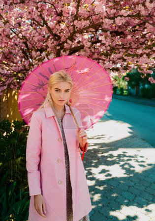Foto de Moda de chicas de primavera. Hermosa joven en vestido rosa en huerto de flores con flores rosadas - Imagen libre de derechos