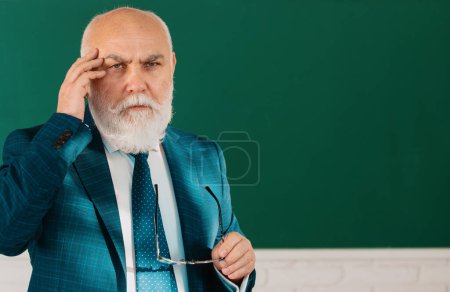 Foto de Profesor de pensamiento masculino mayor de pie frente a una pizarra en un aula. Piensa en senior. Concepto de trabajo y aprendizaje del profesorado - Imagen libre de derechos