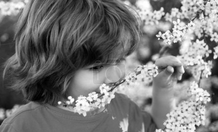 Foto de Chico de primavera en el parque floreciente. Lindo chico al aire libre. Árbol floreciente en jardín - Imagen libre de derechos