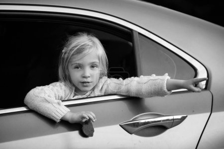 Foto de Niña mira por la ventana en el coche y algo muestra una mano - Imagen libre de derechos