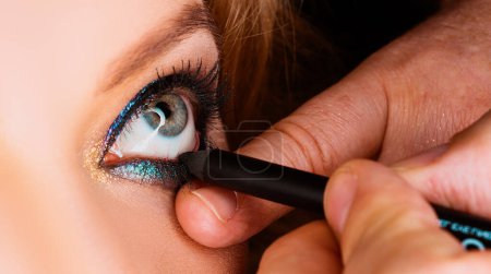 Foto de Maquilla los ojos. Primer plano de los ojos. Aplicación de eyeligner, maquillaje vadage - Imagen libre de derechos