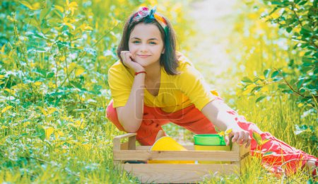 Téléchargez les photos : Portrait d'un enfant jardinier portant récolté à la ferme. L'enfant passe du temps dans le verger. Enfant agriculteur dans la ferme avec une formation à la campagne - en image libre de droit