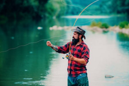 Téléchargez les photos : Pêche. L'homme brutal se tient dans l'eau de la rivière. Homme barbu pêcheur. Un homme pêche sur le lac. Hobby pour l'âme. Fais-le seulement. Pêcheur attrapant le poisson. Unis à la nature. Pêche à la mouche - en image libre de droit