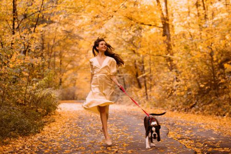 Photo for Young woman with the dog in the park. Wind in the hair. With dog on a walk in an autumn nature. Young beautiful female having fun in autumn park. Girl enjoy walk with dog. Favorite pet - Royalty Free Image