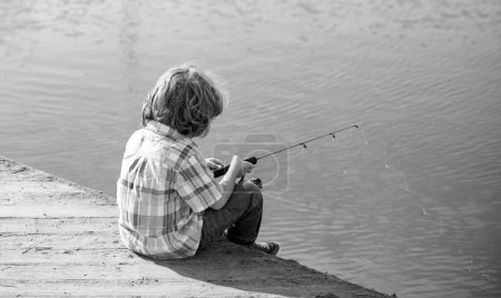 Photo for Child fishing. Young fisher. Boy with spinner at river. Portrait of excited boy fishing. Boy at jetty with rod. Fishing concept - Royalty Free Image