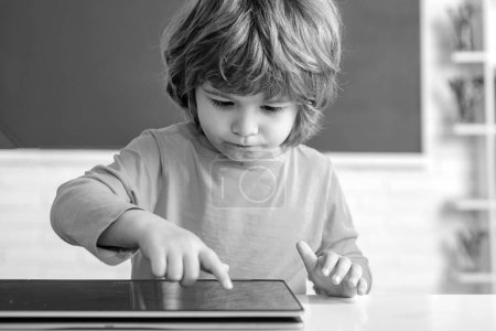 Foto de Niño escolar con tableta en el aula de la escuela. Alumno en clase usando tableta digital. Retrato de alumno de primaria en el interior. Concepto de educación para niños - Imagen libre de derechos