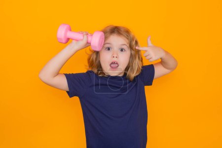Photo for Portrait of sporty child with dumbbells, isolated on yellow studio background. Child boy pumping up biceps muscles with dumbbell - Royalty Free Image