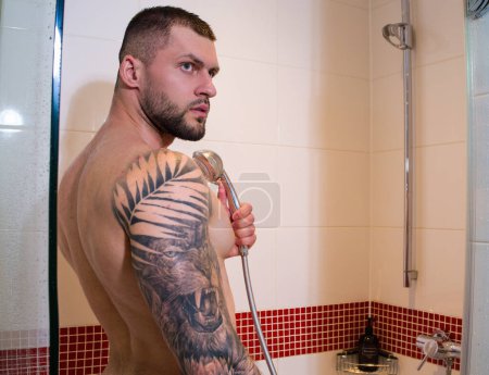 Foto de Retrato de hombre desnudo sexy tomando ducha en el baño. Rutina de higiene masculina. Hombre sexy con lavado corporal muscular húmedo en la ducha. Un tipo en la ducha. Un hombre tomando una ducha caliente. Rutina matinal - Imagen libre de derechos