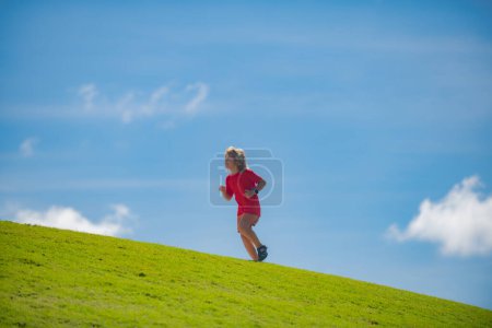 Photo for Cute boy running across grass and summer sky. Sporty kid running in nature. Active healthy child boy runner run outdoor - Royalty Free Image