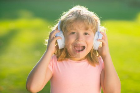 Photo for Screaming excited kid in headphones listening to music in backyard - Royalty Free Image