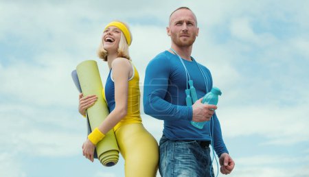 Photo for Sporty funny couple with dumbbell outdoors. Athletic young happy couple holding dumbbells and fitness mat outdoor - Royalty Free Image