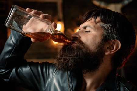 Photo for Drinking man is cheking his phone. Man holding a glass of whisky. Sipping whiskey. Degustation, tasting. Barbershop. Shaving. Portrait of a handsome man with beard - Royalty Free Image