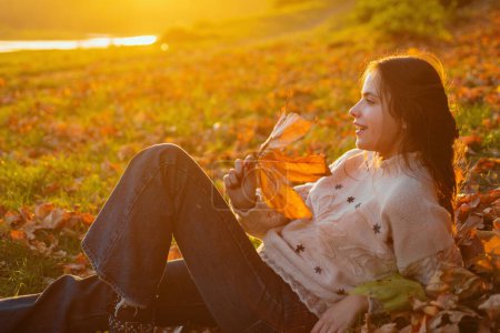 Photo for Warm moments of autumn. Woman pretty girl enjoy autumn. Girl relaxed lay fallen leaves on sunny autumn day. Warmth and coziness. Female autumn leaves background. Catching evening sunbeams. - Royalty Free Image