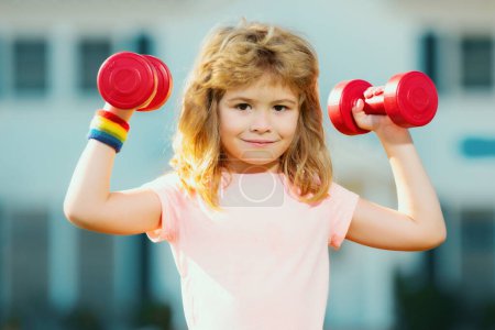 Photo for Sport exercise for kids. Sporty children, healthy Lifestyle. Child boy lifting dumbbells outside. Funny excited child sportsman - Royalty Free Image
