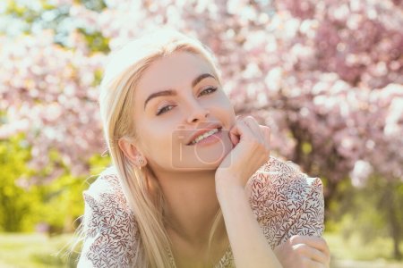 Foto de Chica feliz con flores en la hierba. Linda cara de joven sonriente en primavera. Mujer de sueño - Imagen libre de derechos