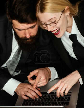 Foto de Dos socios de negocios trabajando juntos con el portátil. Mujer de negocios sonriente y su colega mirando el portátil. Un par de jóvenes diseñadores trabajando en el portátil - Imagen libre de derechos