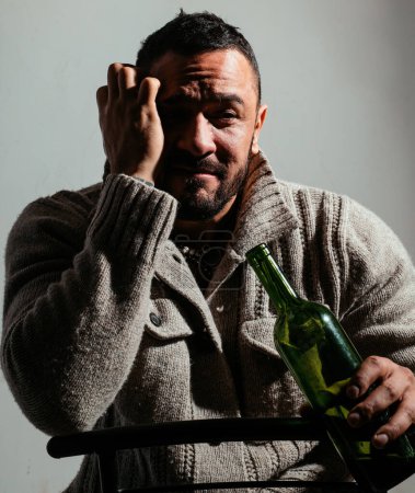 Photo for He is a recovering alcoholic. Depressed latino man drinking alcoholic drink from bottle. Anonymous alcoholic having drinking problem. Alcoholic personal degradation. - Royalty Free Image