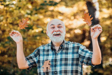 Photo for Elderly man smiling outdoors in nature. Grandfather relaxing in autumn park. Freedom retirement concept. Senior man walking in the park in autumn - Royalty Free Image