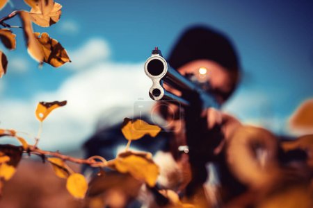 Photo for Poacher with Rifle Spotting Some Deers. Hunter with shotgun gun on hunt. Autumn - Royalty Free Image