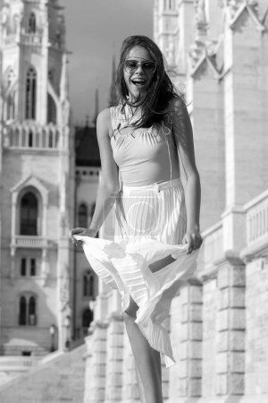Foto de Hermosa modelo femenina en la ciudad de verano en Europa. Mujer de moda posando en el fondo de la calle. Movimiento excitado lanzamiento mujer asombrada - Imagen libre de derechos