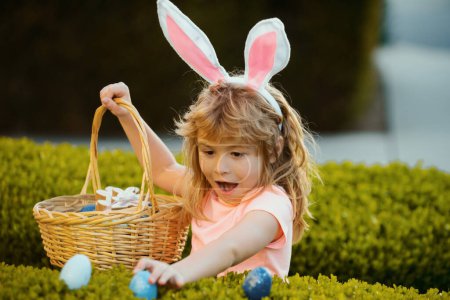 Photo for Child gathering eggs, easter egg hunt concept. Easter bunny kids. Kids in bunny ears on Easter egg hunt in garden - Royalty Free Image