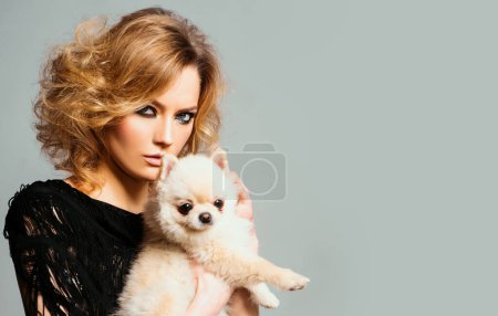 Foto de Mujer de moda con perrito. A los perros les encanta. Hermosa mujer joven sosteniendo cachorro en las manos. Día Nacional de las mascotas. Animales de amor - Imagen libre de derechos