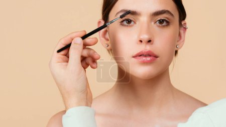 Téléchargez les photos : Woman eye with beautiful eyebrows. Perfect shaped brow, eyelashes with brow gel brush. Female model shaping brown eyebrows - en image libre de droit