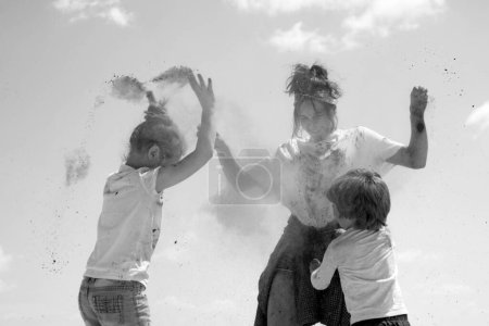 Téléchargez les photos : Enfants excités joyeux émotionnels avec poudre colorée et éclaboussure de poussière de couleur - en image libre de droit