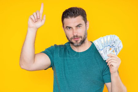 Photo for Handsome man holding money isolated over grey studio. Money in dollar banknotes. Pile of cash, finance, investment and money saving - Royalty Free Image
