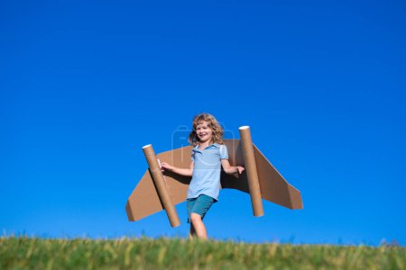 Téléchargez les photos : Joyeux enfant jouant avec jetpack jouet. Le pilote s'amuse en plein air. Succès enfant, innovation et leader. Concept créatif et start-up - en image libre de droit