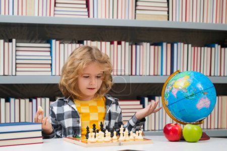 Téléchargez les photos : Ecole d'échecs pour enfants. Intelligent concentré et pensant gamin jouant aux échecs. Enfants développement du cerveau et jeu de logique - en image libre de droit