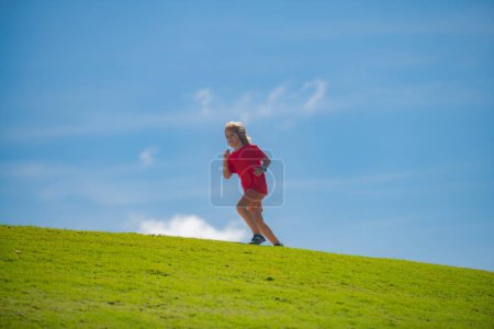 Photo for Cute boy running across grass and summer sky. Sporty child boy runner running in summer park. Active kids, sport children - Royalty Free Image
