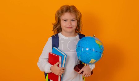 Photo for School kid portrait. Schoolboy with world globe and book. School child student with backpack. Elementary school child. Portrait of pupil on yellow studio isolated background - Royalty Free Image